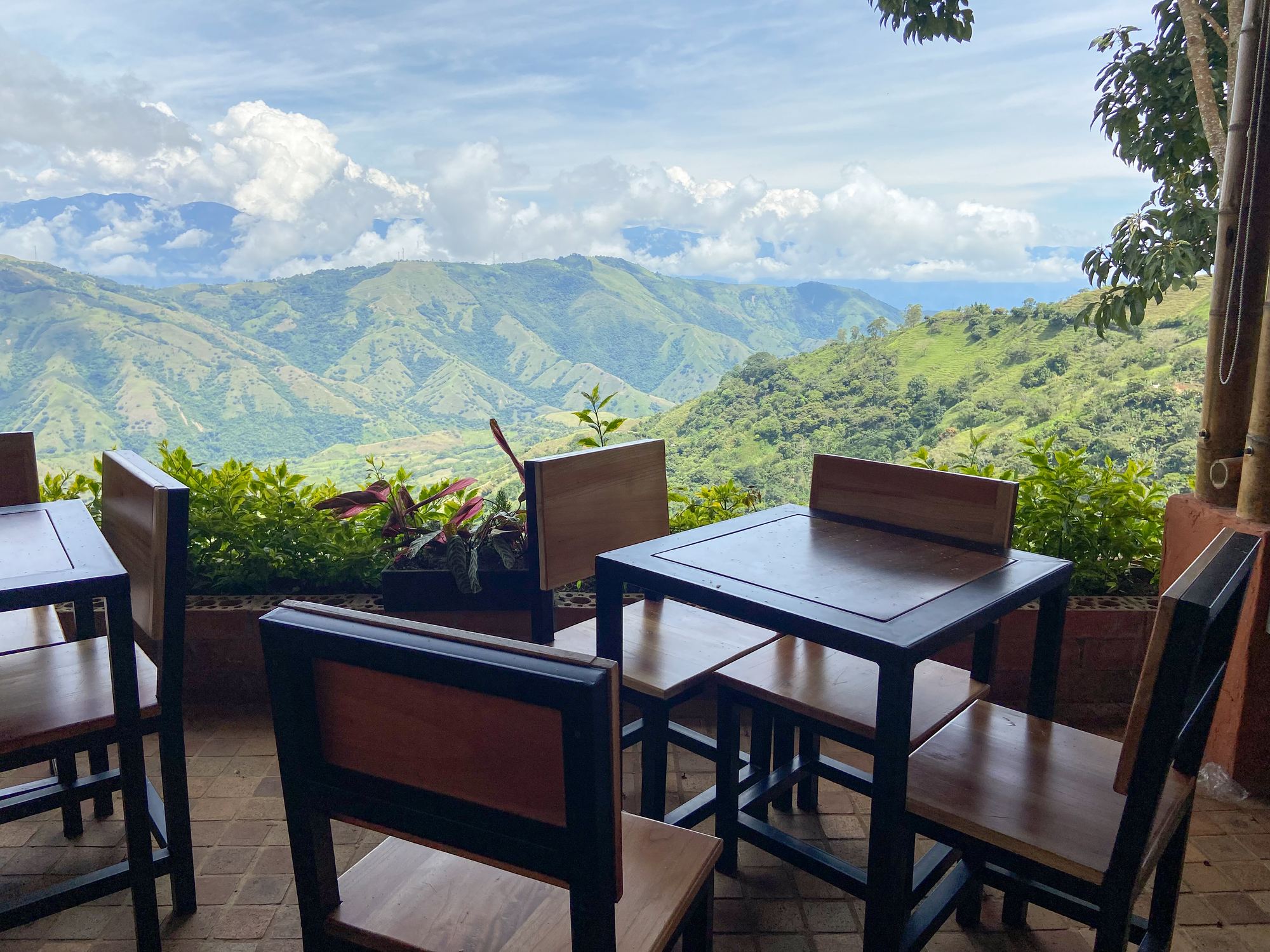 Dining terrace with wooden tables facing a wide mountain valley
